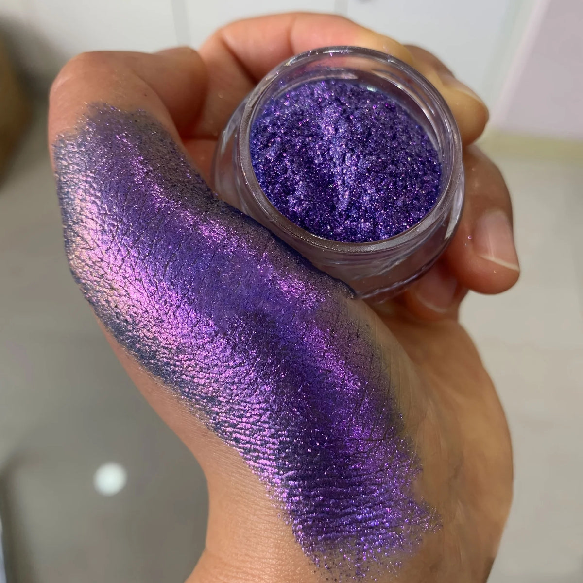 Polvo glitter aurora camaleón vibrante, degradado multicolor, tonos mora, morado, azul y verde, maquillaje corporal deslumbrante