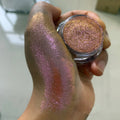 Polvo glitter aurora camaleón vibrante, degradado multicolor, tonos mora, morado, azul y verde, maquillaje corporal deslumbrante
