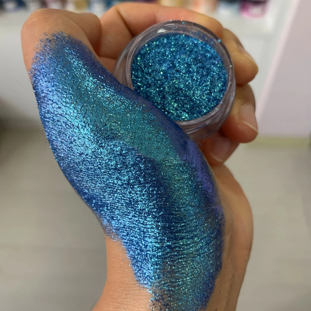 Polvo glitter aurora camaleón vibrante, degradado multicolor, tonos mora, morado, azul y verde, maquillaje corporal deslumbrante